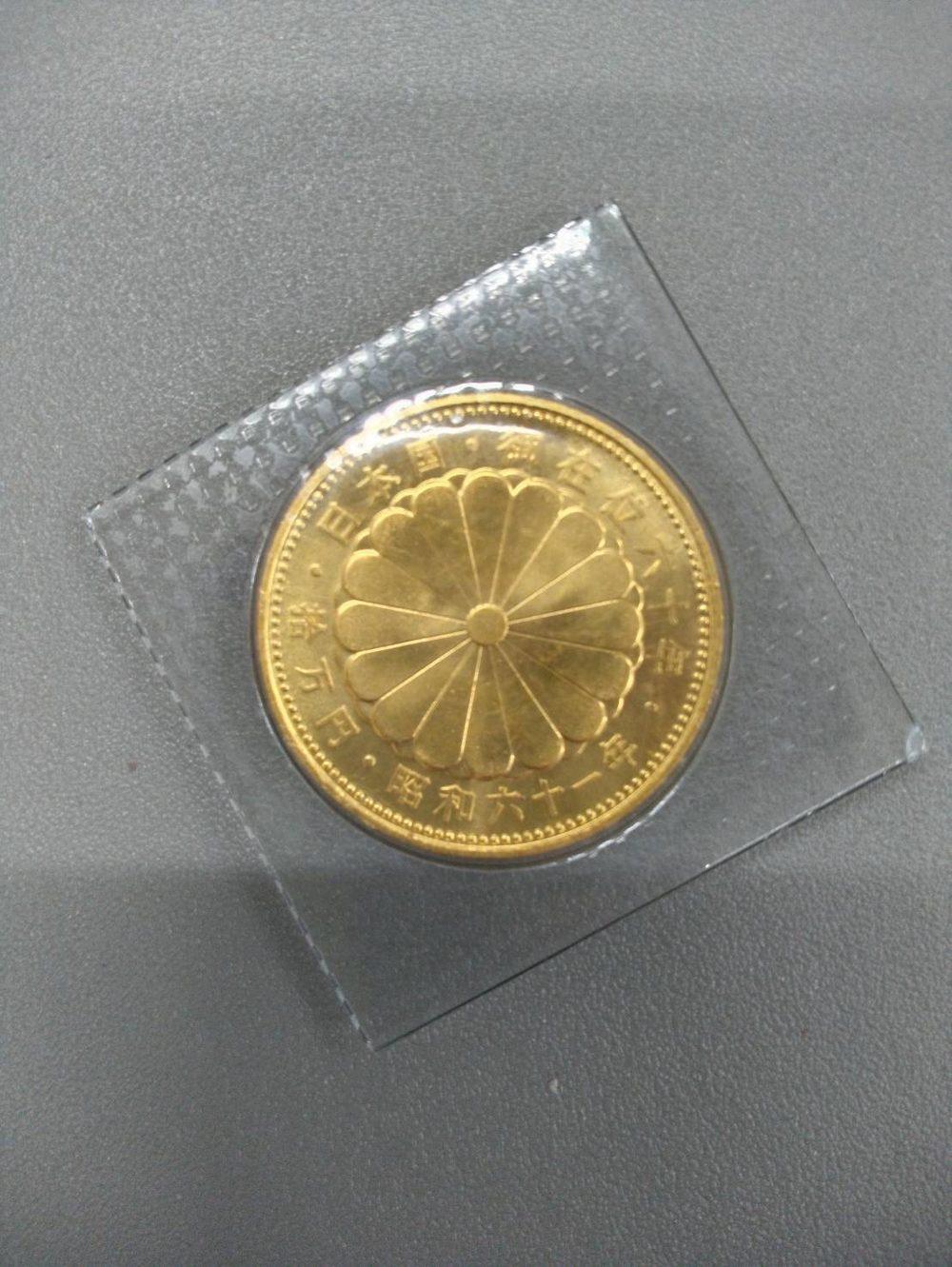 10万円金貨の菊の紋章の面に刻まれた 日本国 御在位六十年 拾万円 昭和六十一年 の文字