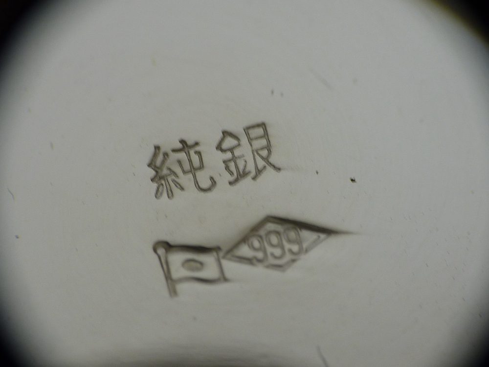 銀杯に打たれた「純銀」の文字と、日の丸の旗、ひし形の中の999の刻印